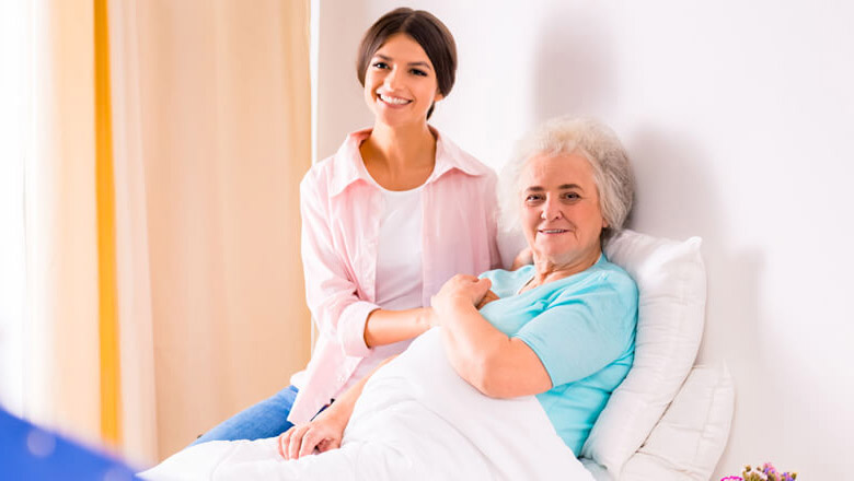 Cuidado Sênior - Cuidadora hospitalar segura a mão de idosa acamada com delicadeza, transmitindo apoio emocional em ambiente tranquilo e iluminado.