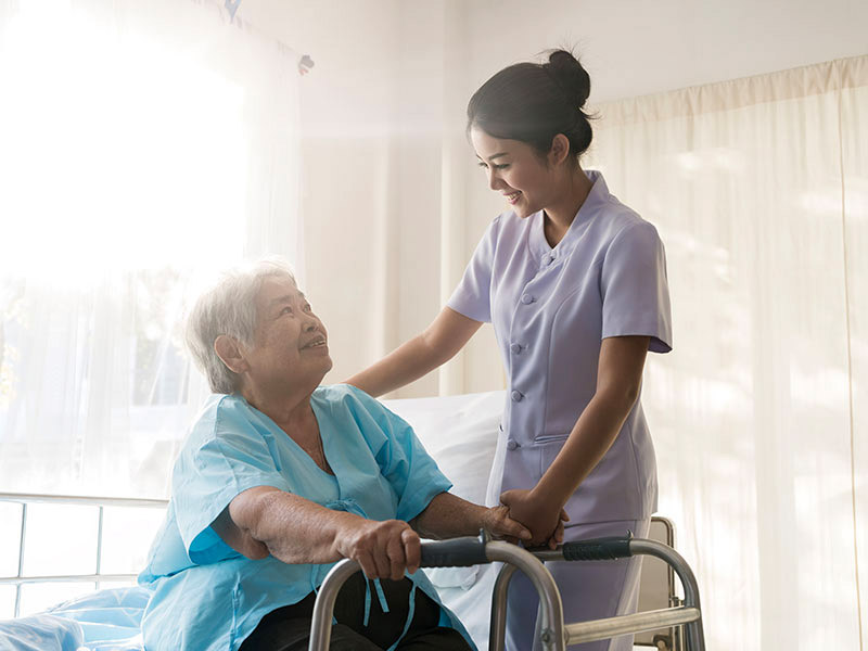 Cuidadora da Cuidado Sênior atenciosa ajuda idosa com andador, em ambiente claro e acolhedor, representando cuidado humanizado e profissional.