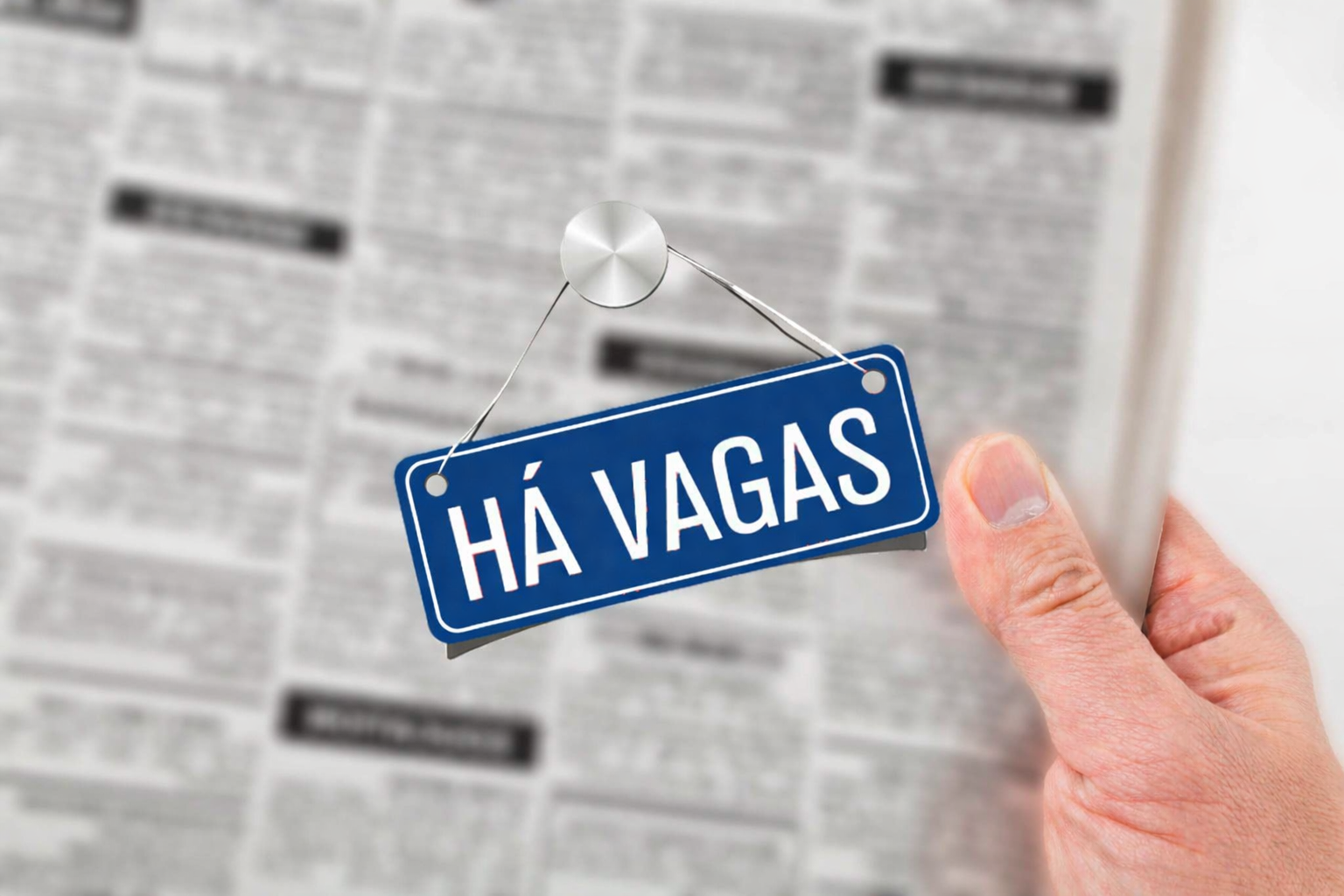 Cuidado Sênior – Placa azul com os dizeres "HÁ VAGAS", segurada por uma mão sobre fundo de jornal de classificados